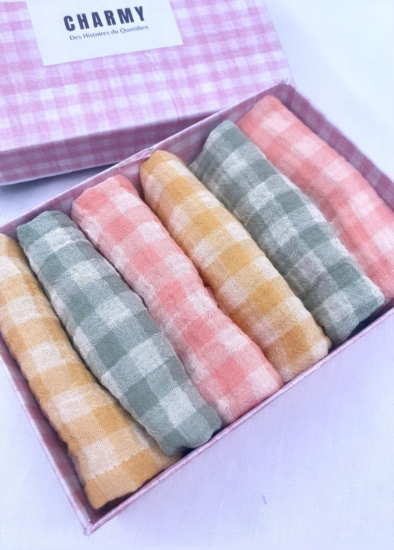 coffret type boîte de 6serviettes de table en tissu. Elles sont roulées dans la boîte, il y a 2 serviettes vichy vert de gris, 2 rose barbapapa et 2 jaune blé
