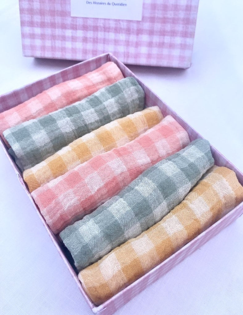 coffret type boîte de 6serviettes de table en tissu. Elles sont roulées dans la boîte, il y a 2 serviettes vichy vert de gris, 2 rose barbapapa et 2 jaune blé