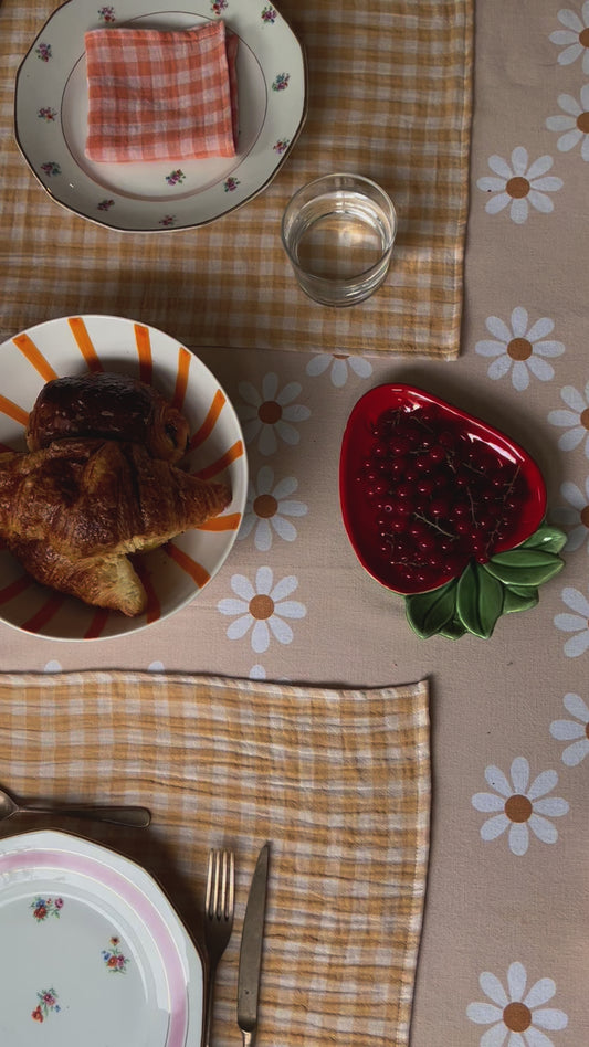 table de brunch avec des sets de tables en tissu jaune blé et une nappe orange pale à fleurs